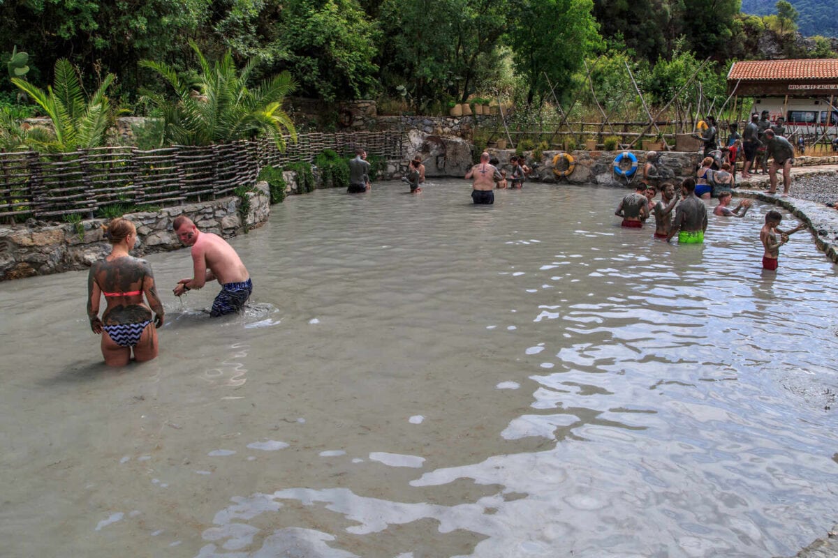 Crowd of people in a muddy pool with greenery around