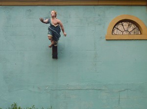 boat figurehead depicting a woman, projecting from a blue wall