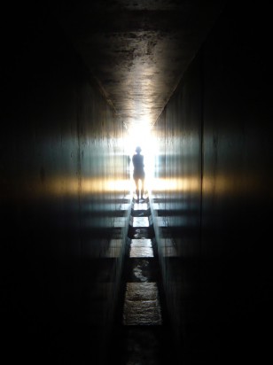 woman's silhouette against entrance to dark passage