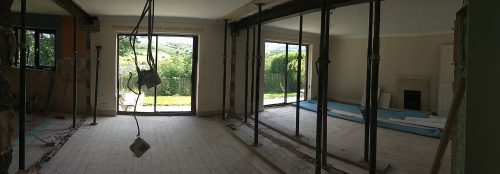 A panorama shot as you enter a room that has been clearly openened up. There are studs holding metal beams up still at this point where once load bearing walls had been.