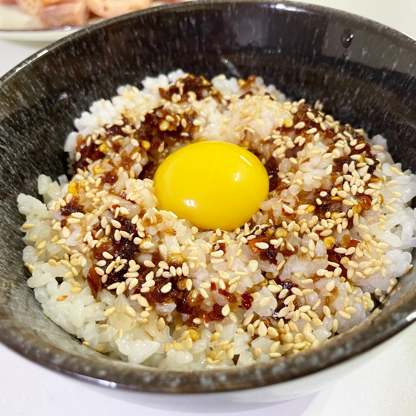 a bowl of steamed rice with sesame seeds, homeade chilli oil and raw egg yolk