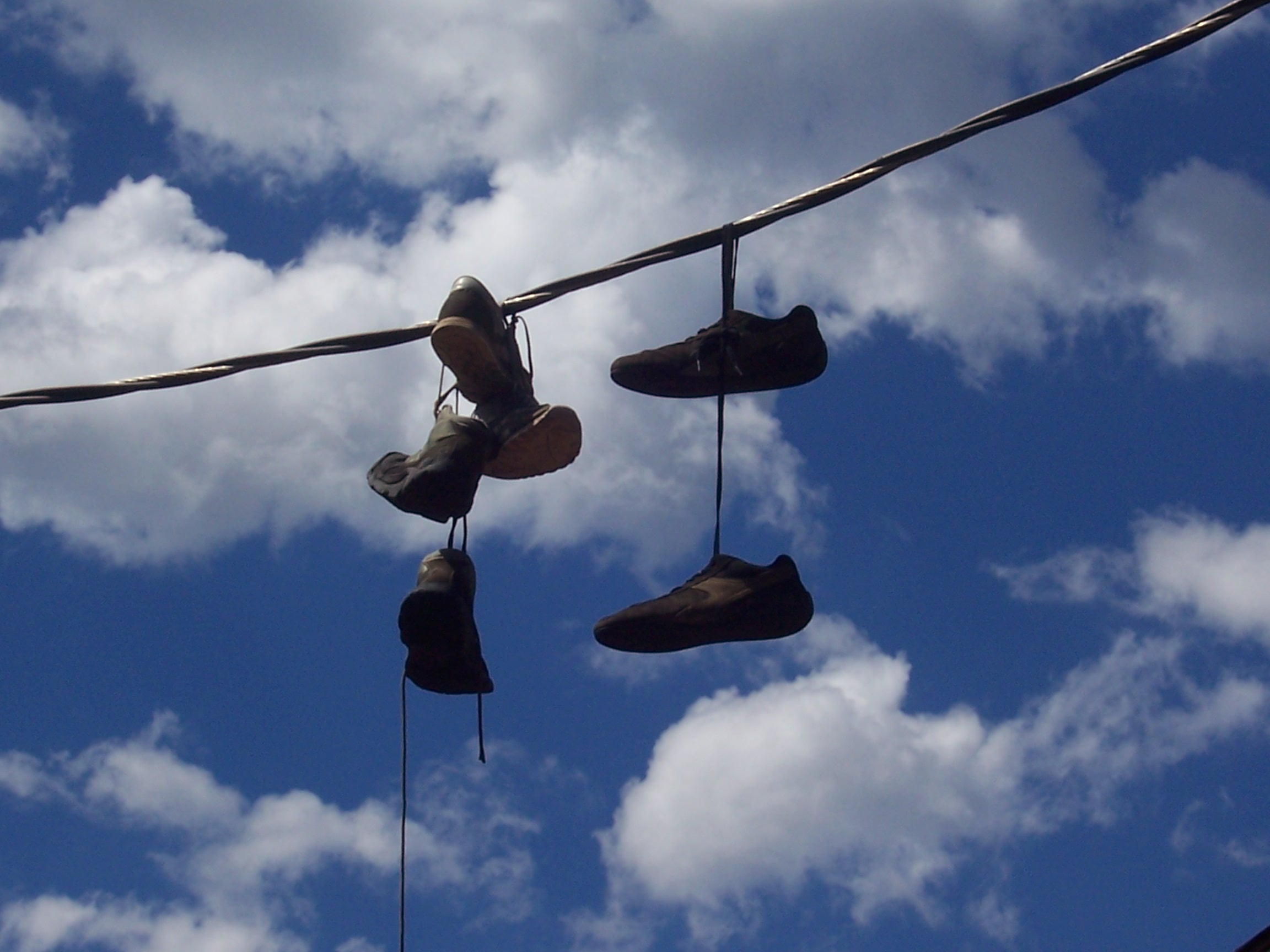 Drei Paar Schuhe über einem Kabel