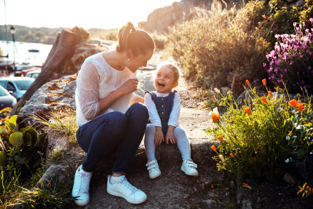 Maman rigolant avec sa petite fille lors d'un coucher de soleil