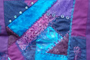 Pude med crazy patchwork og maskinbroderi og håndbroderi. Nelliker