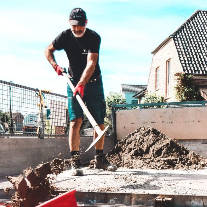 Medewerker van Juma Tuinen is aarde aan het uiladen in een kruiwagen