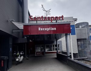 Eingang zum Santapark mit rotem Schild „Reception“ und Rentierfigur oben auf dem Dach.