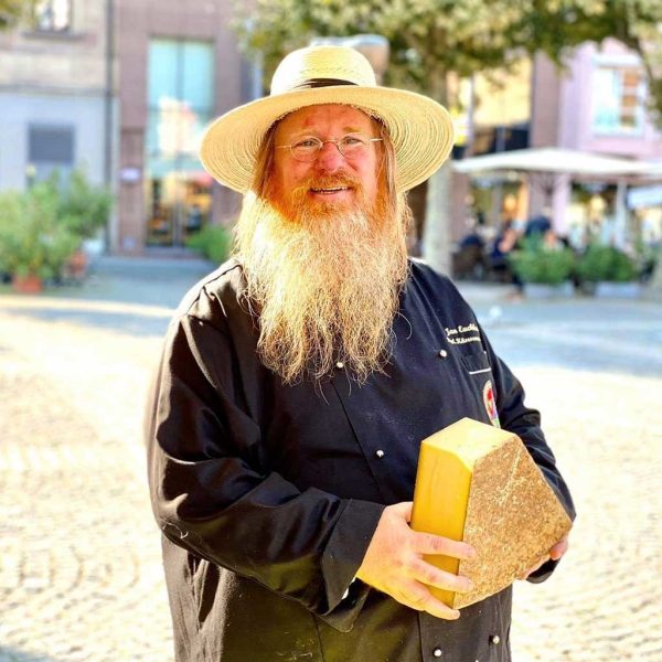 Käseonkel auf Wochenmarkt Heilbronn mit großem Stück Käse in der Hand