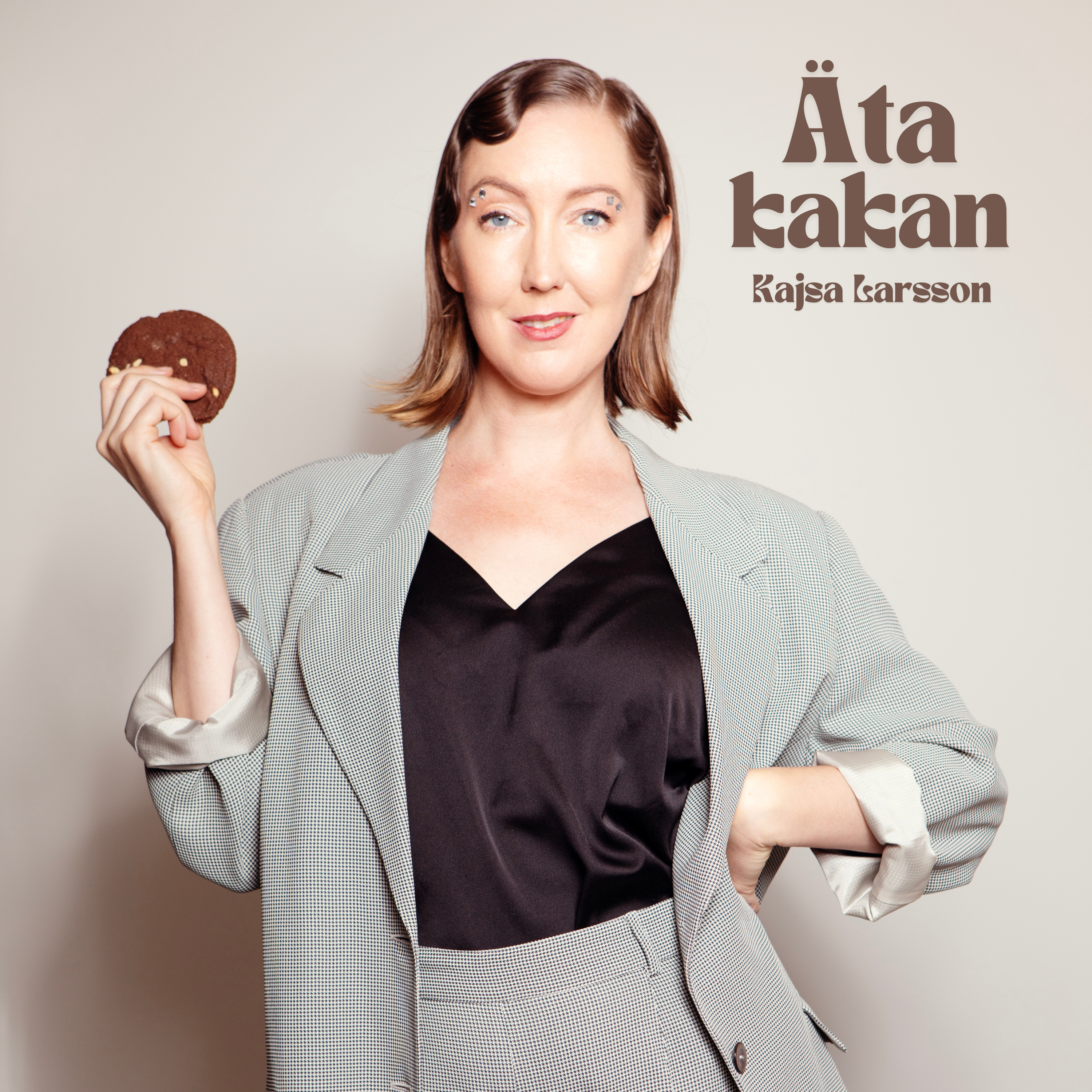 Omslag till singeln Äta kakan ute 11 okt. Kajsa står med en kak i handen och tittar in i kameran. Texten på bilden säger Äta kakan, Kajsa Larsson