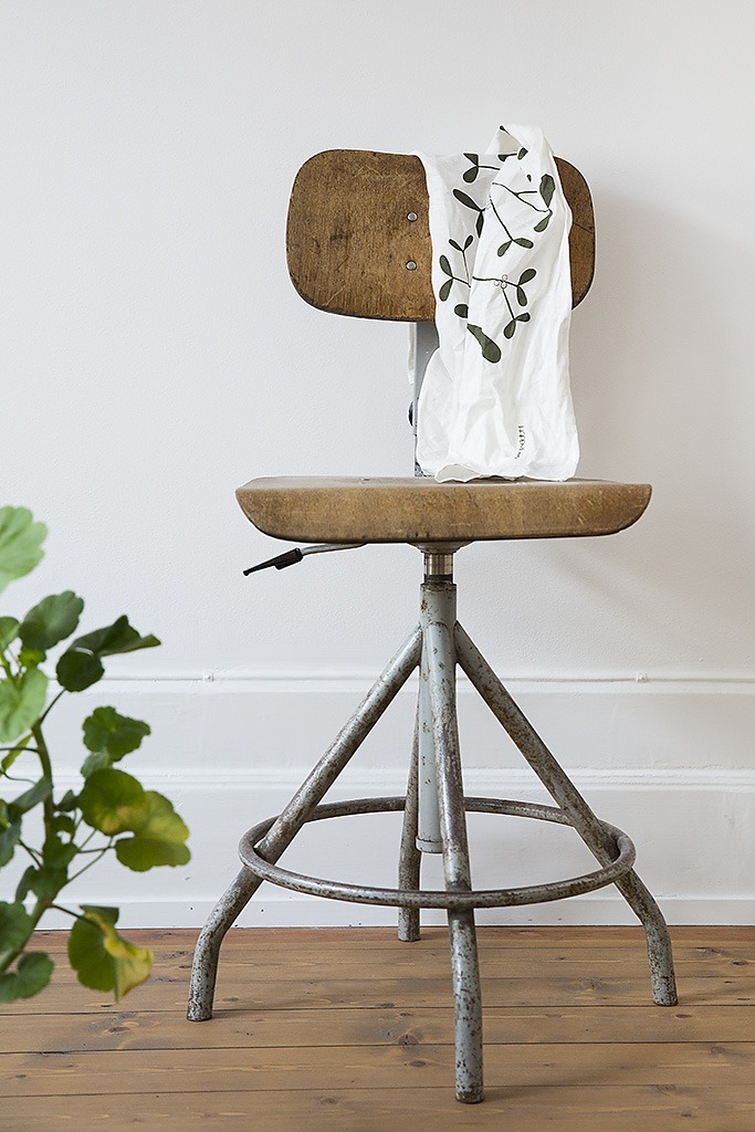 kökshandduk med mönster av mistel som hänger på stol design och formgivning för HAPPYSthlms kollektion