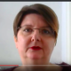 Ein Screenshot des Skype-Interviews mit Denise. Denise trägt eine Brille ohne Rahmen, roten Lippenstift und hat kurzes braunes Haar