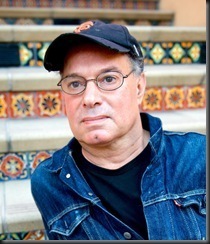 A man with a black cap and glasses sits on stairs