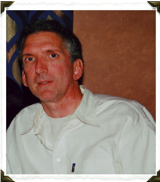 Image of a man with blackish/grey short hair and a white sweater.