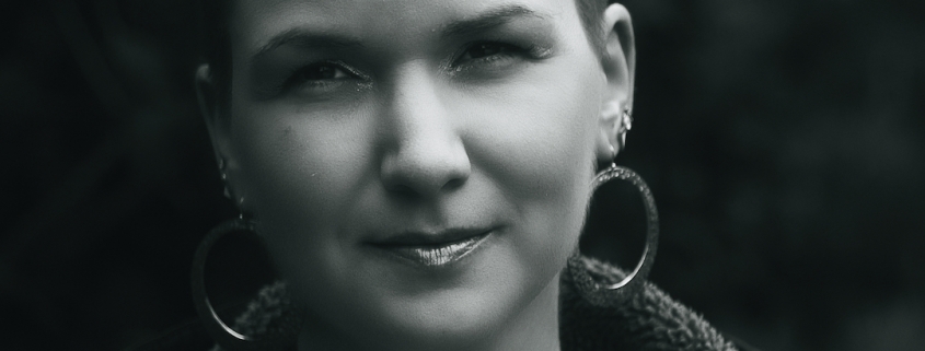 Black and white photo of Karina, a woman with 7 mm shaved hair and huge round earrings.