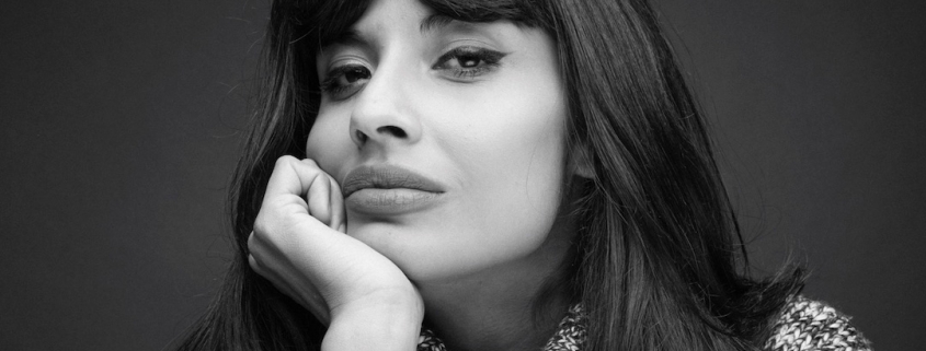 A black and white shot of Jameela, a woman with long black hair who rests her head on her hand