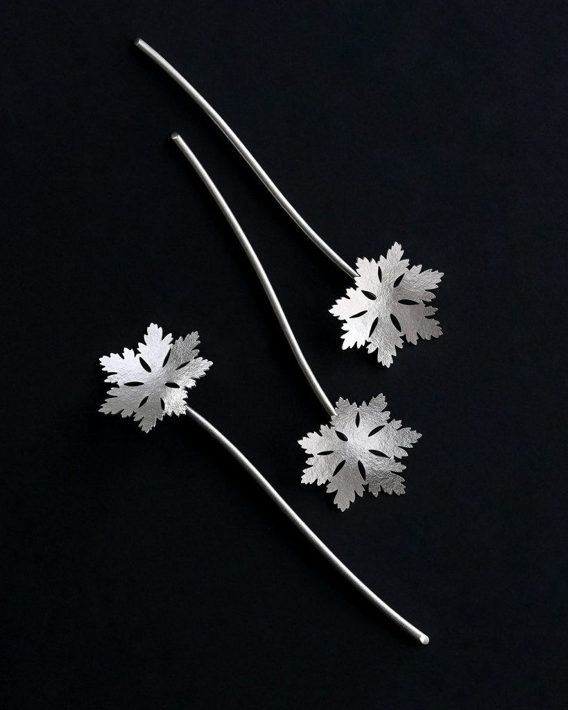 Tre hårpinnar med motiv av flocknäva gjorda av silver i numrerad upplaga av silversmed och smyckekonstnär Katarina Henriksson