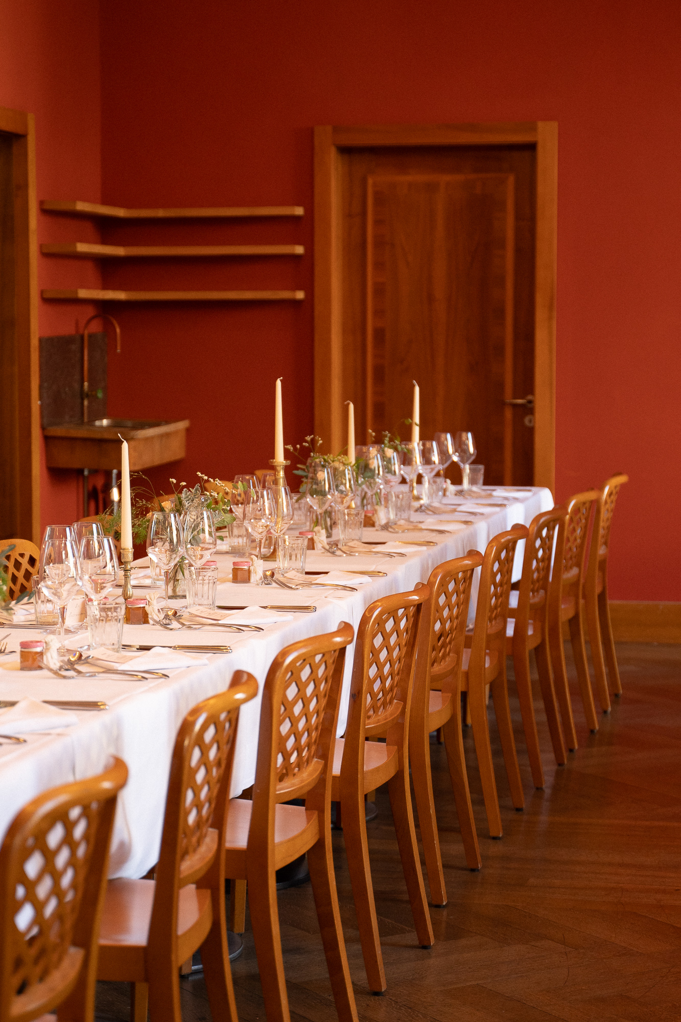 Einer geschmückte Hochzeitstafel im roten Salon. Hochzeitsfotografin Katharina Schillinger hat dieses Bild aufgenommen in Basel im Unternehmen Mitte. Fotografie Katharina Schillinger in Basel Schweiz