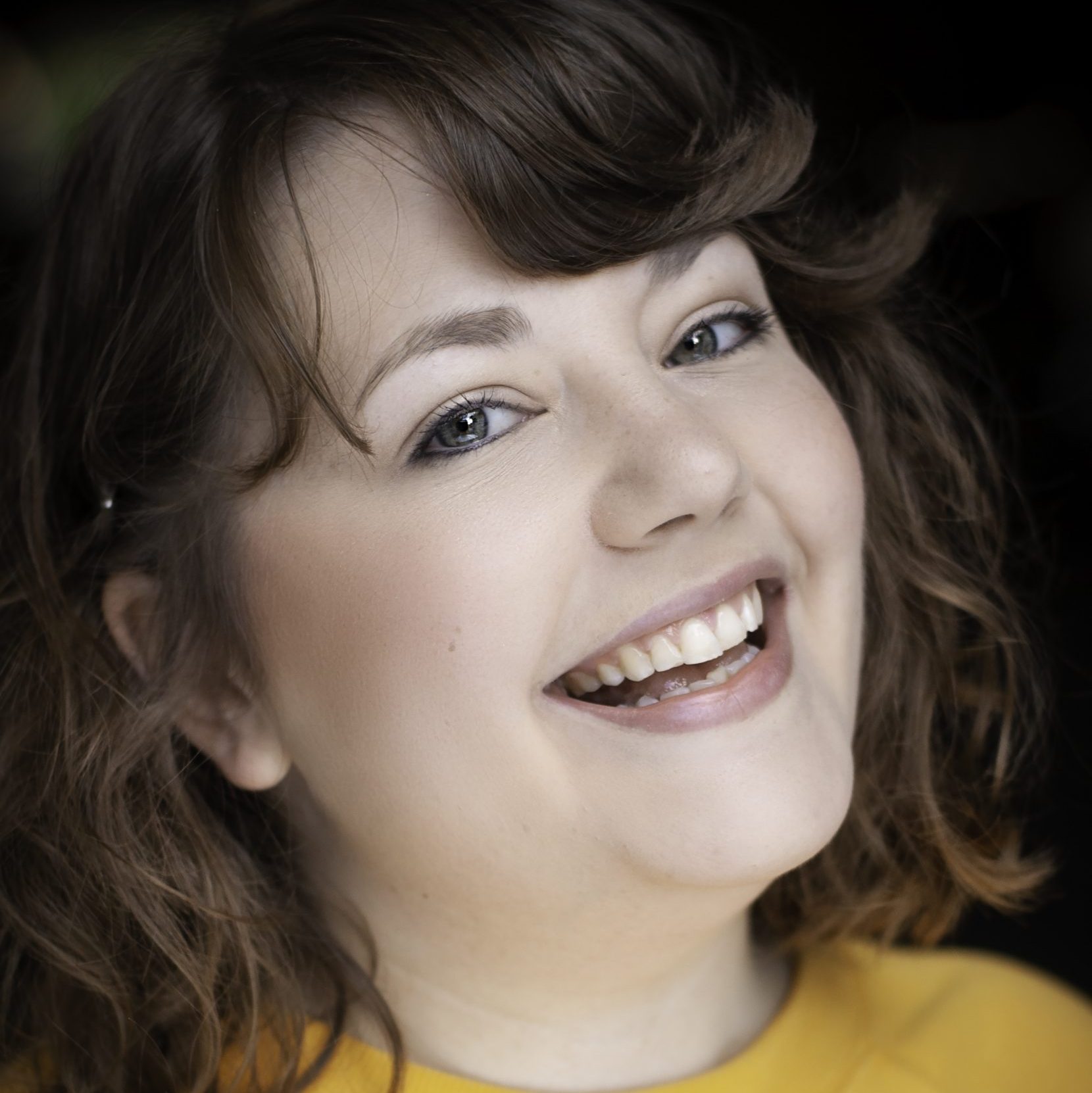 My acting headshot. Here I am smiling wearing a mustard yellow jumper.