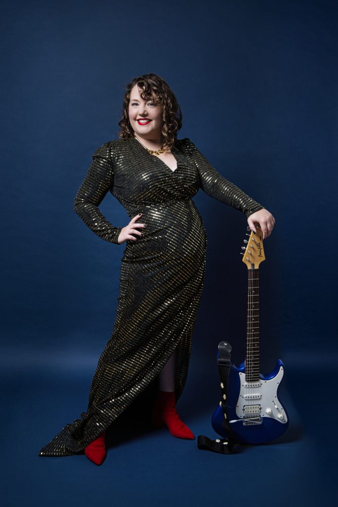 Here I am in my gold sequinned ball gown with my little red boots peeping through. I am leaning on my electric blue electric guitar.