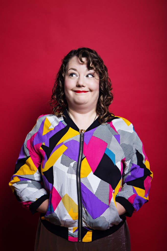 Here I am in my multicoloured bomber jacket with a bright red background. I look like I have caused some shenanigans as I'm peering very cheekily to my right.