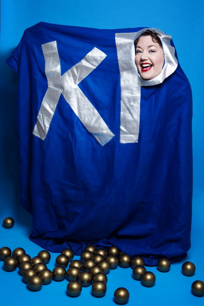 Here I am in my hand made KP Nuts packet featuring a big blue duvet cover, onto which I have hand sewn big shiny silver letters of K and P. My head is poking through the hole in the letter P, and there are giant nuts (golden balls) on the floor surrounding me.