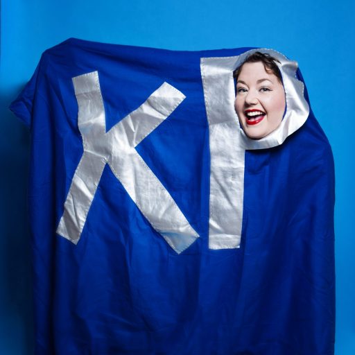 Me inside a blue duvet cover with the letters K and P sewn onto it, with my head poking out of the middle of the letter P