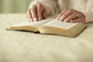 Senior man reading Bible, close-up of hands