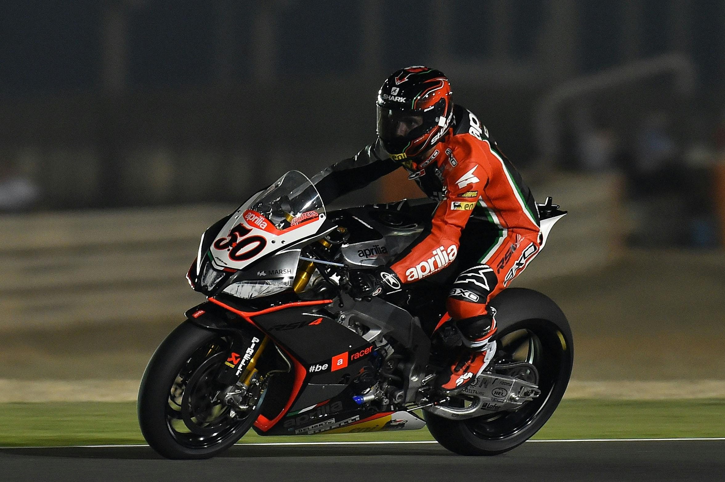 Motorcycle racer in action on the track at night, showcasing speed and skill under stadium lights.