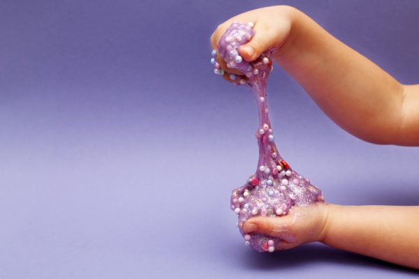 Making slime at home. child holding and stretching colorful slime.