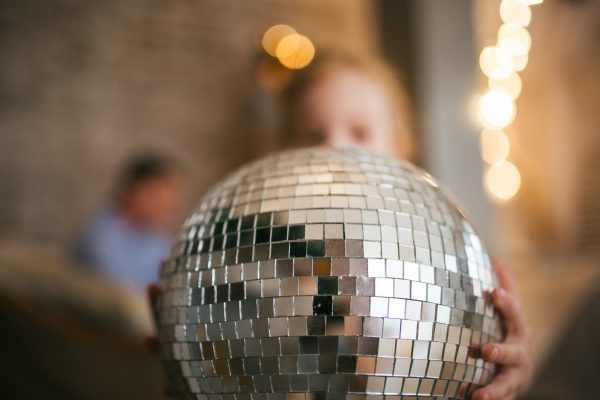 The child is holding a disco ball in his hands. Celebration and shine
