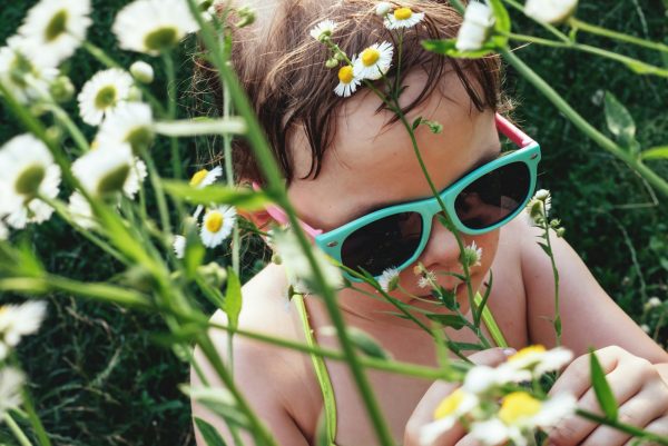 Portrait of a child in sunglasses in daisies flowers