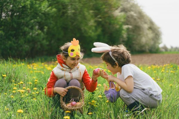 Two children hunt for Easter eggs in a spring garden. Easter tradition