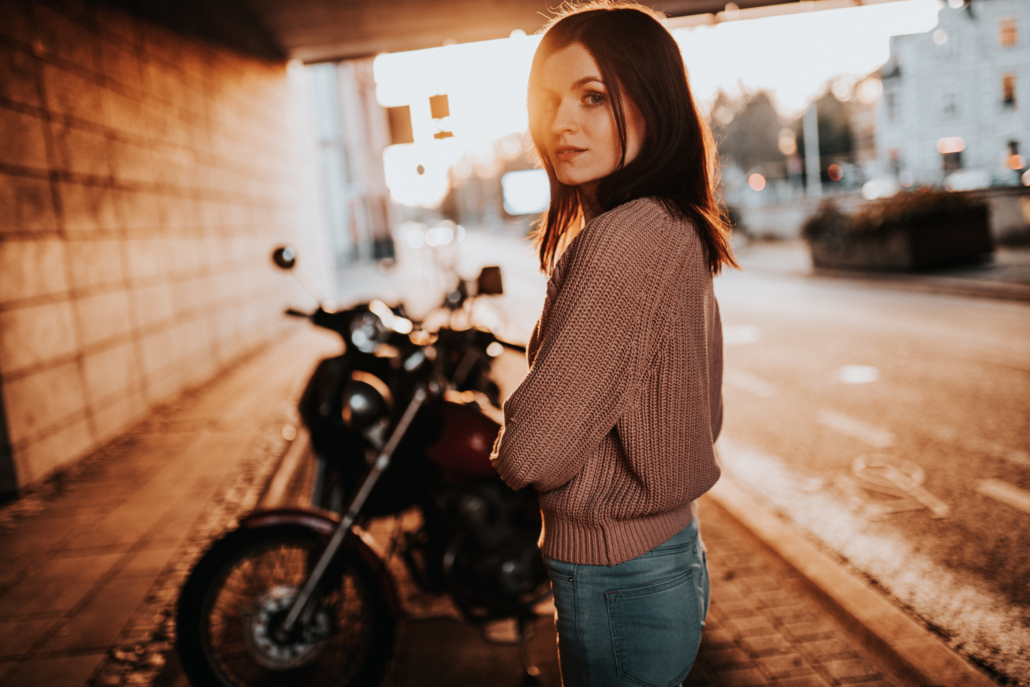 Frau mit Sommersonne und Motorrad im Hintergrund