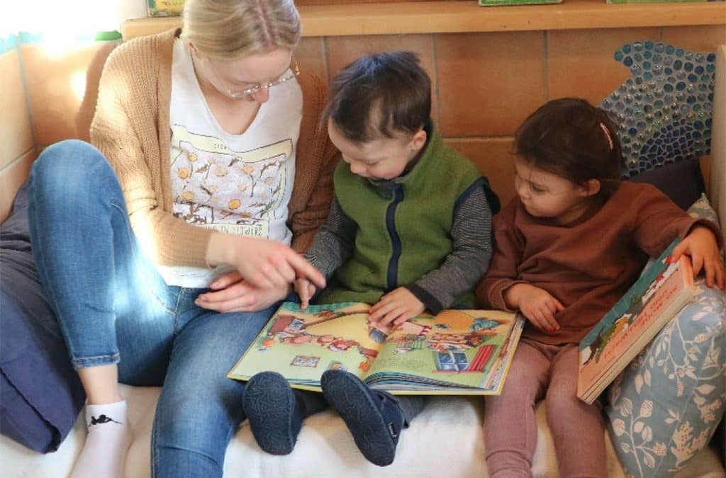 Eine Erzieherin liest Kindern ein Bilderbuch vor