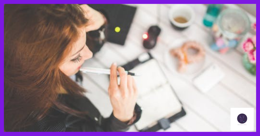 Image shows a woman at her desk trying to think of new blog topic ideas