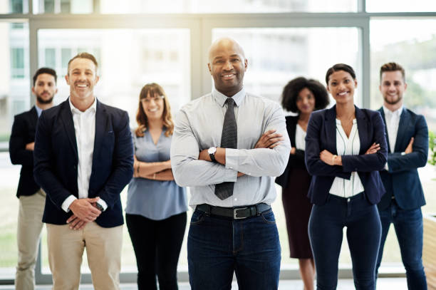 Portrait of a mature businessman standing in an office with his colleagues in the background