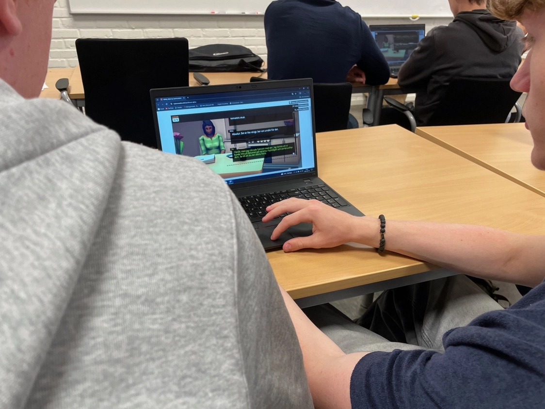 Två studenter tittar på en laptop-skärm som visar ett klimatspelet utbildningsspel.