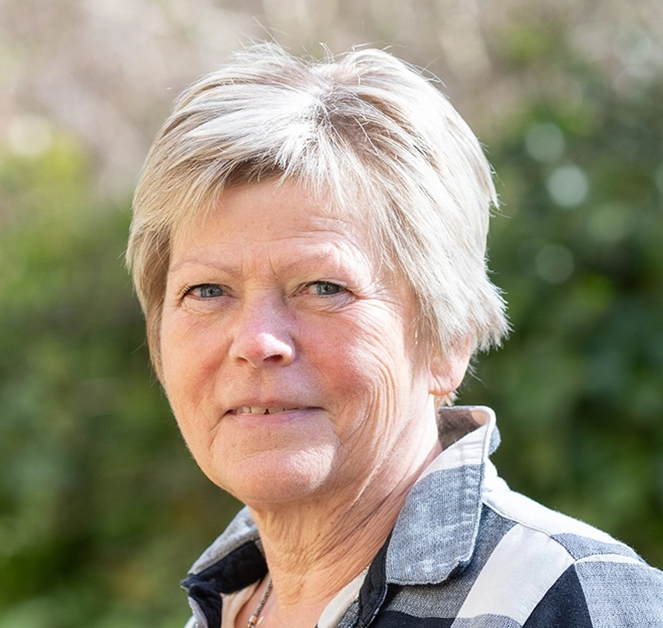 Birgitte Schantz Laursen, smilende kvinde i 50erne med kort gråt hår stående i grøn natur