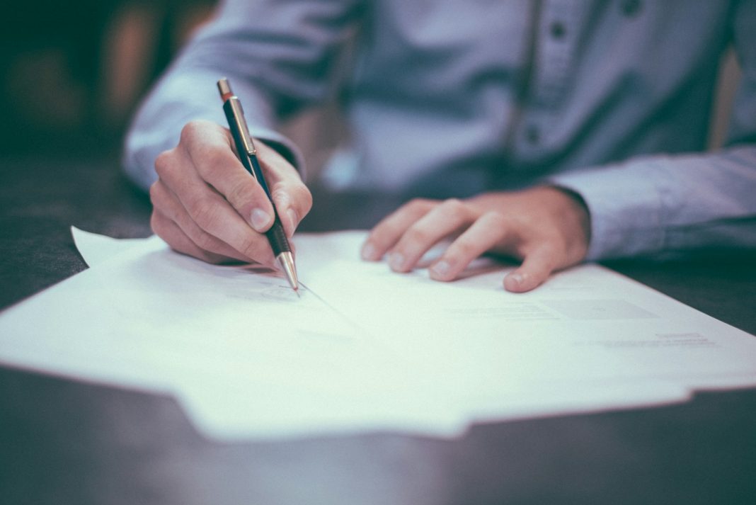 Handen die officiële stukken ondertekenen op een kantoorbureau
