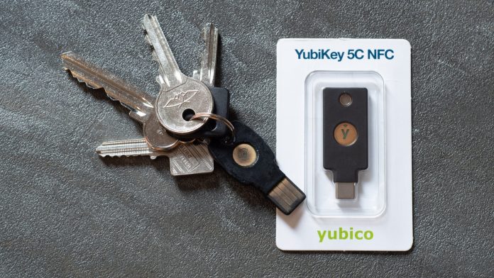 USB-beveiligingssleutel (YubiKey) op een bureau naast een laptop