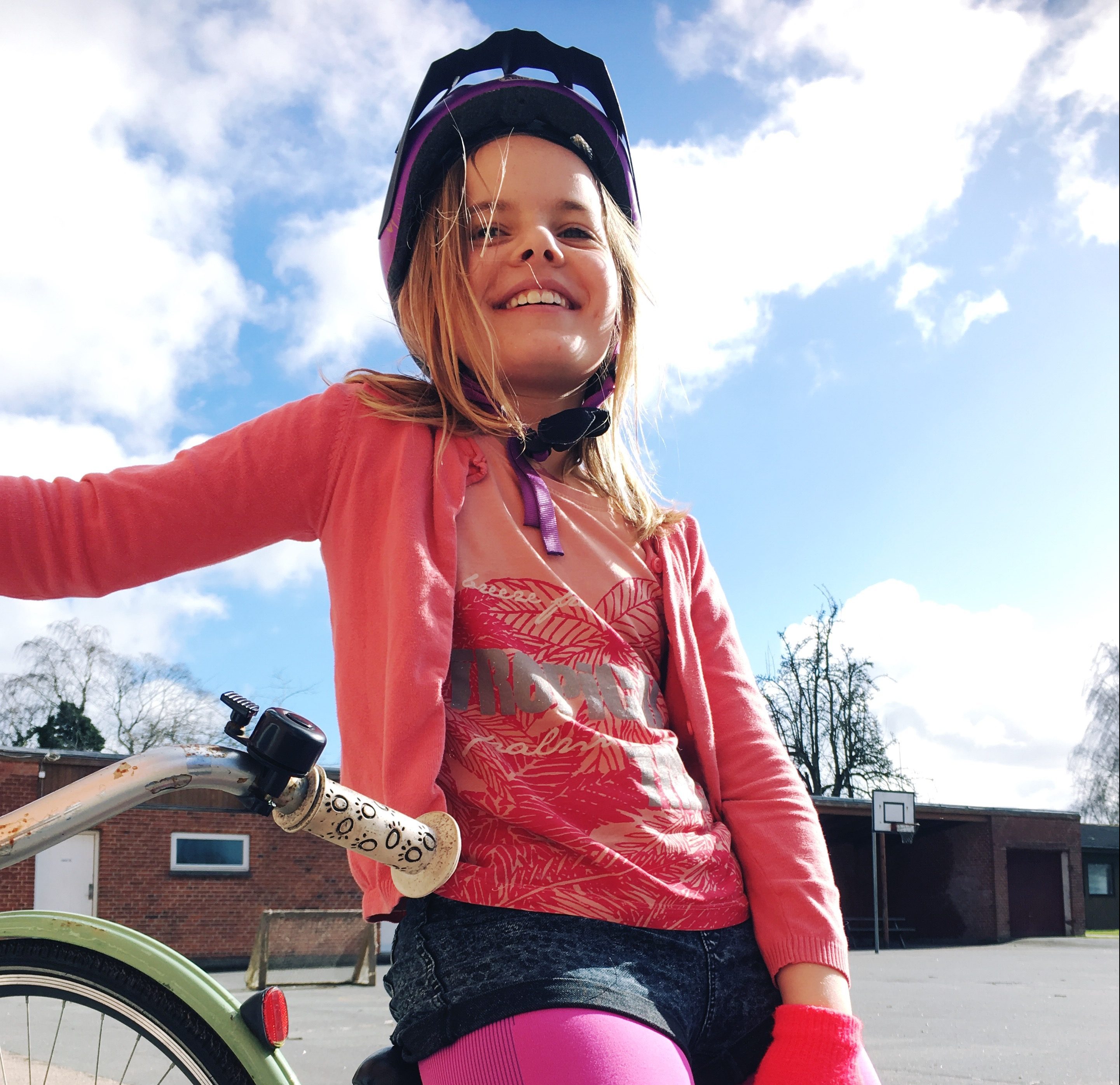 Pige med cykelhjelm og cykel, solskinsdag