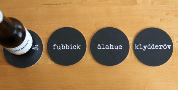 Fyra svart glasunderlägg med svart text med orden möghong, fubbick, ålahue och klydderöv.