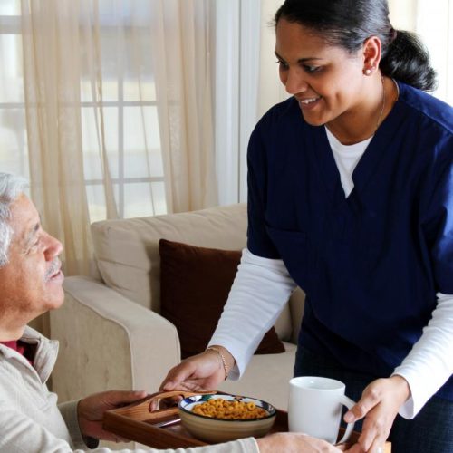 older-man-with-tray-near-woman-in-blue-scrubs