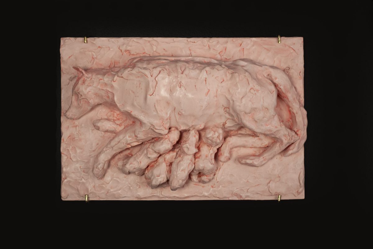 A wall sculpture made from Jesmonite and pigment showing a wolf feeding wolflings and a human baby