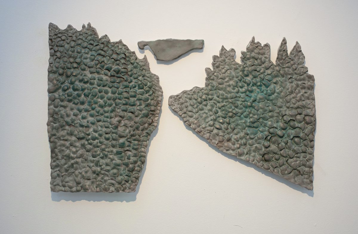 A wall sculpture made from Jesmonite and broze showing the silouette of a road