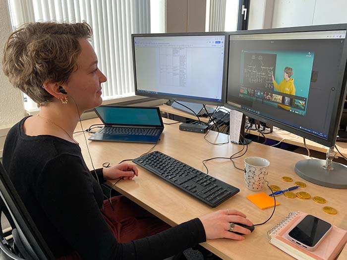 Een foto van Justine die achter haar bureau naar een filmpje kijkt dat zij heeft gemaakt