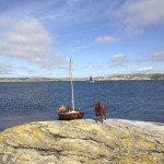 rocky island in skagerrak sea with boat and dog
