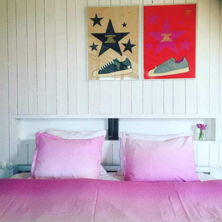 dubbelsäng i väst rum på Lådfabriken -creative seaside accommodation- med rosa bäddlinnen av Designer's Guild och med adidas-konst på väggen
