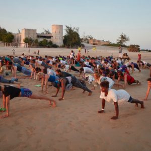Multiple participants having a yoga session on the beach during a retreat