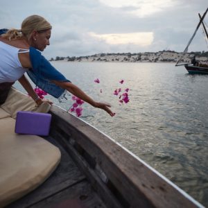 A woman throwing flower petals in the ocean in a sunset cruise during a retreat activity