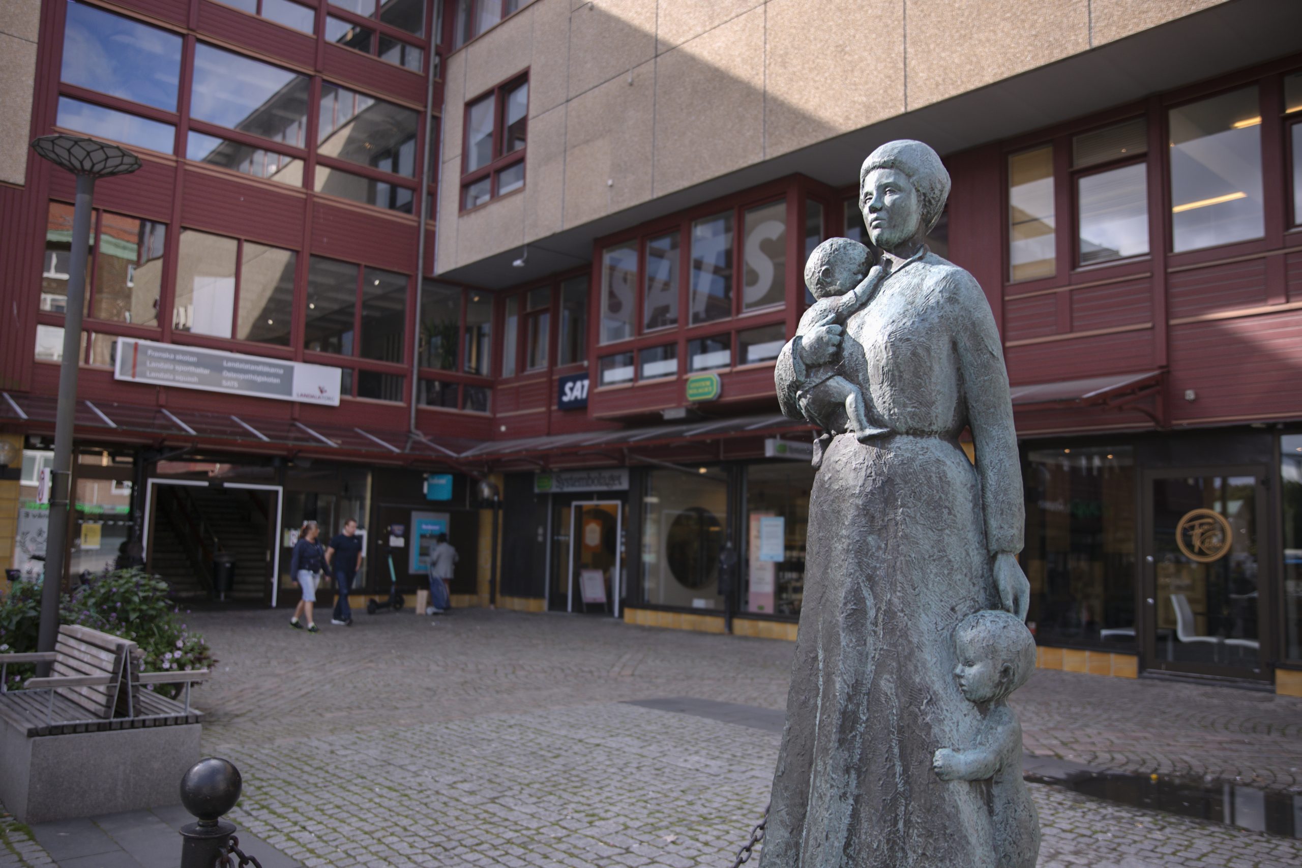 Ett foto av en torgyta med en skulptur föreställande en kvinna och barn.